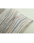 Chunky ivory cushion cover featuring flowy lines in warm tones of brown, blue, and pink, measuring 18x18 inches.