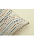 Chunky ivory cushion cover with flowy lines in warm tones of brown, blue, and pink, perfect for home decor.