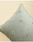 Hand-embroidered evil eye cushion cover on mint green velvet, adding elegance and protection to any space.