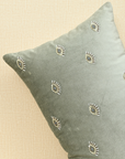 Hand-embroidered evil eye cushion cover on mint green velvet, adding elegance and protection to any space.