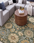Living room with a gray sectional sofa, round wooden coffee table, and patterned rug.