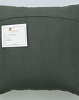 Dark gray pillow with a label on a light gray background
