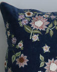 Navy blue pillow with floral embroidery on a plain background