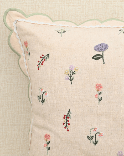 Tea Rose cushion featuring delicate floral embroidery in pink, lavender, and peach with scalloped edges.