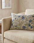 Decorative floral pillow on a beige sofa in a living room setting.