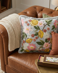 Decorative pillow with floral and lemon design on a brown leather sofa.
