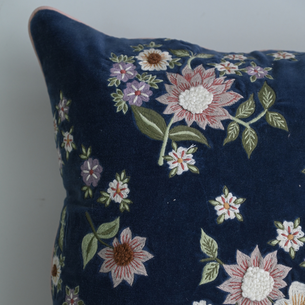 Navy blue pillow with floral embroidery on a plain background