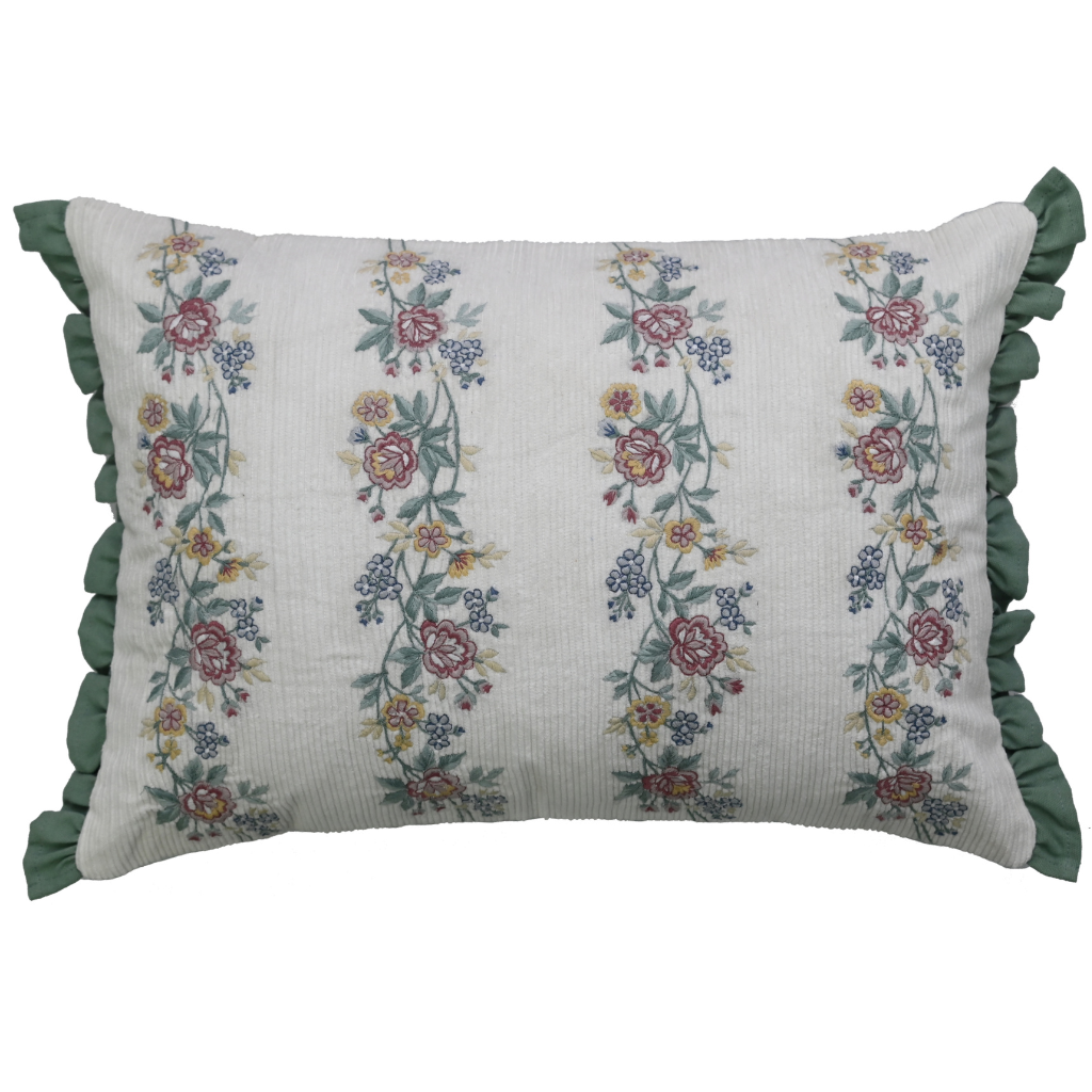 Decorative pillow with floral embroidery and green ruffles on a white background