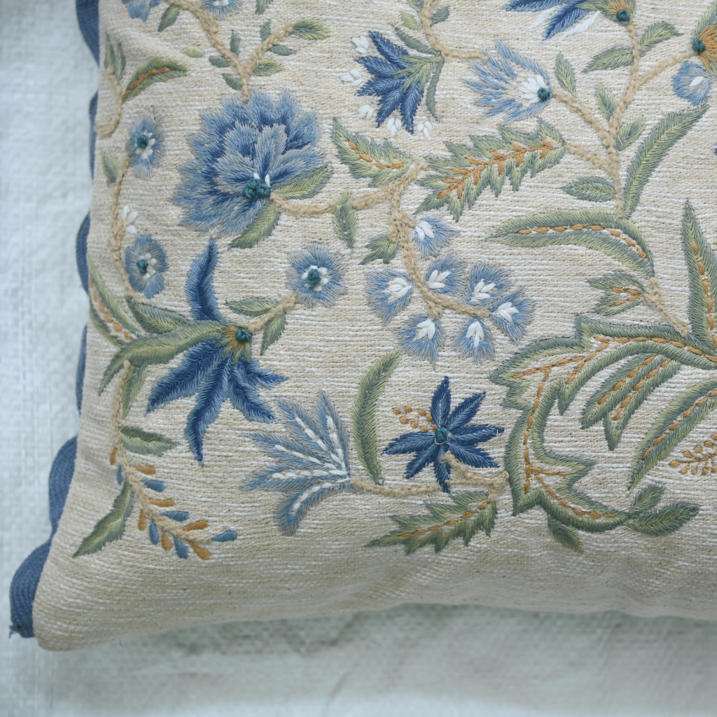 Decorative pillow with floral embroidery on a textured surface